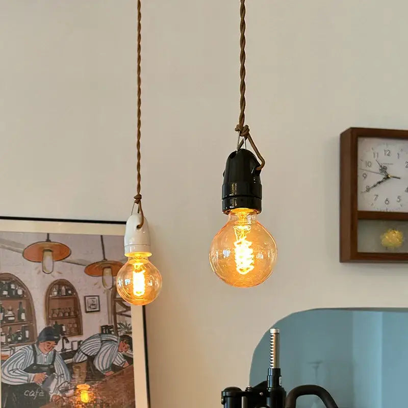 Two vintage japanese ceramic led pendant lights with black metal and white ceramic bases emitting warm yellow light