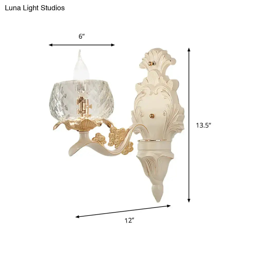 Cream-colored ornate wall light sconce with gold accents and faceted crystal glass shade for bedroom use