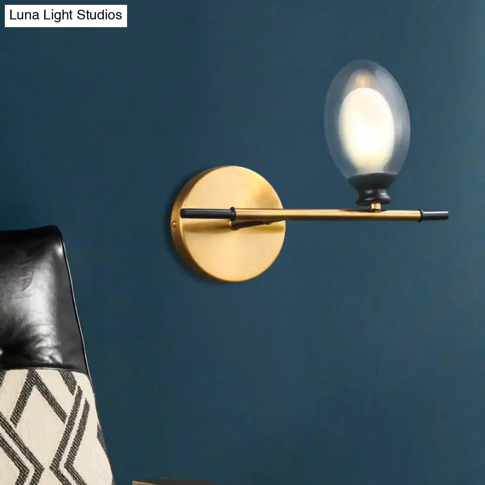 Vintage oval wall sconce in gold-toned brass with a minimalist circular base and frosted glass bulb for bedroom lighting