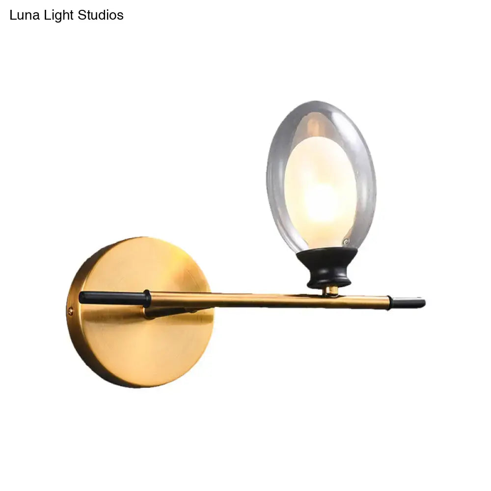 Vintage oval wall sconce in brass and black with a gold-toned circular base and glass globe for bedroom lighting