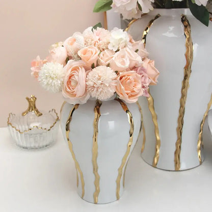 White vintage porcelain vase with gold rim holds soft pink and cream artificial flowers for living room decor
