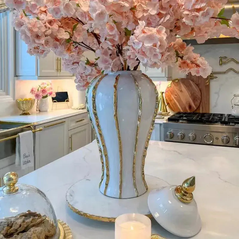 Vintage porcelain vase in white with gold rim vertical stripes holding pink blossoms for living room decor