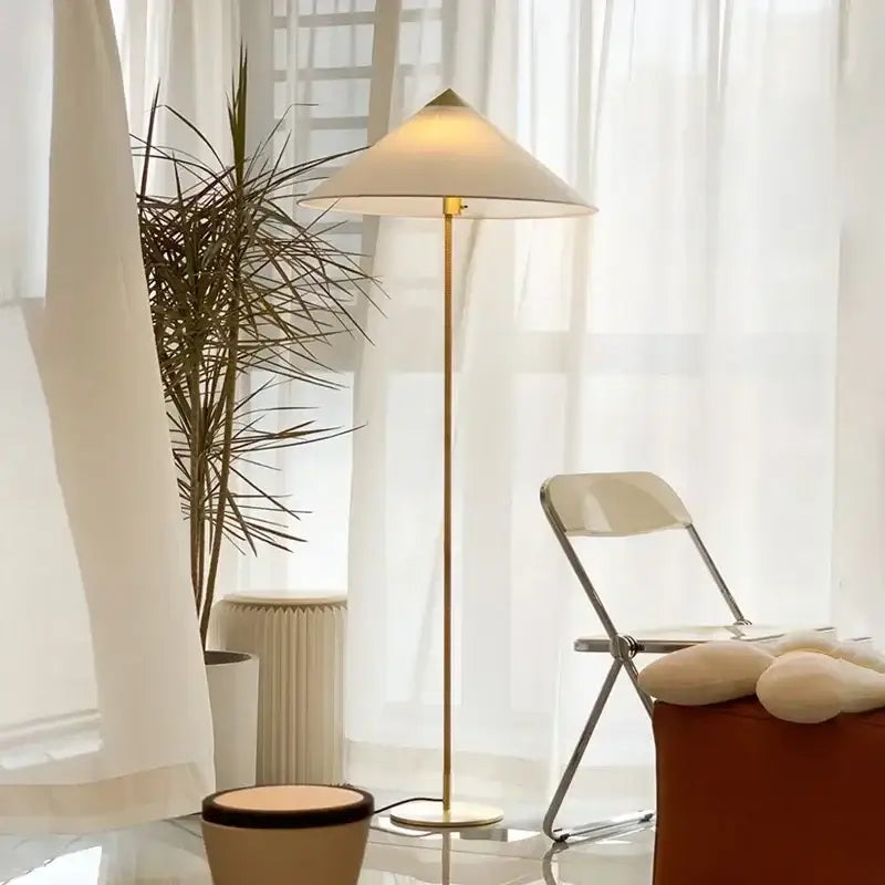 A sleek gold-toned floor lamp with a gubi rattan shade and white fabric for elegant living room decorbites lighting