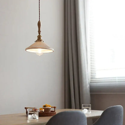 A warm-toned vintage ceramic led pendant light with ribbed shade and brass accents hanging from braided cord