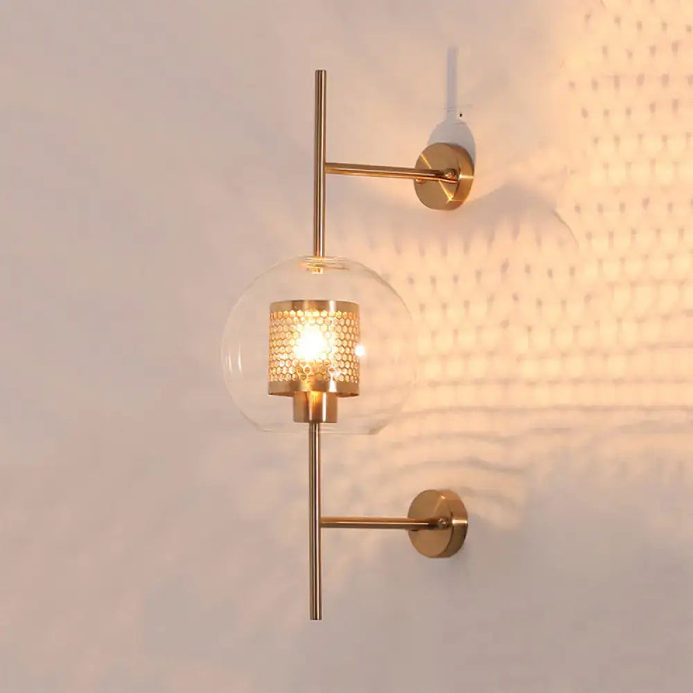 Vintage silver and gold clear glass sconce light with gold-toned wall fixture and illuminated honeycomb-patterned metal shade