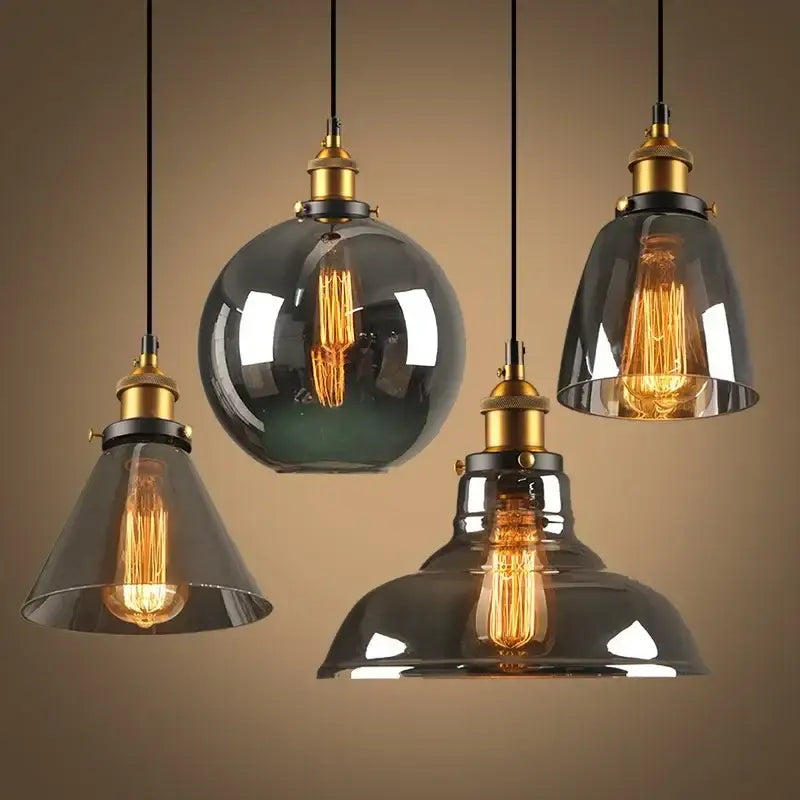 Set of four vintage pendant lights with amber glass shades and brass fixtures featuring exposed filament bulbs