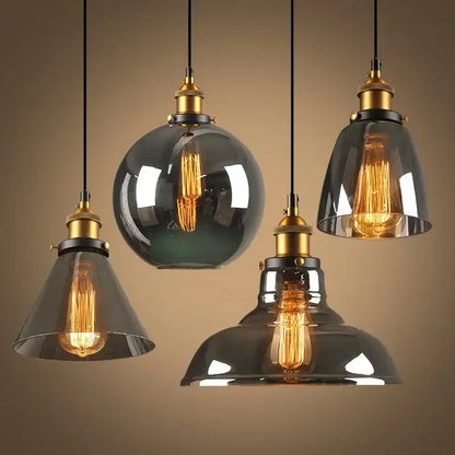 Set of four vintage pendant lights with amber glass shades and brass fixtures featuring exposed filament bulbs