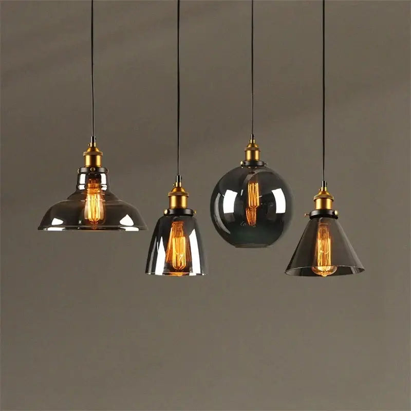 Set of four vintage-style pendant lights with smoked glass ball shades and brass accents for kitchen decorbites