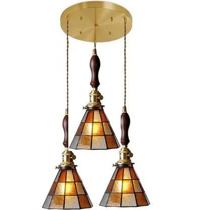 Brass-finished three-light glass copper pendant with amber frosted shades and wood knob switch for kitchen lighting