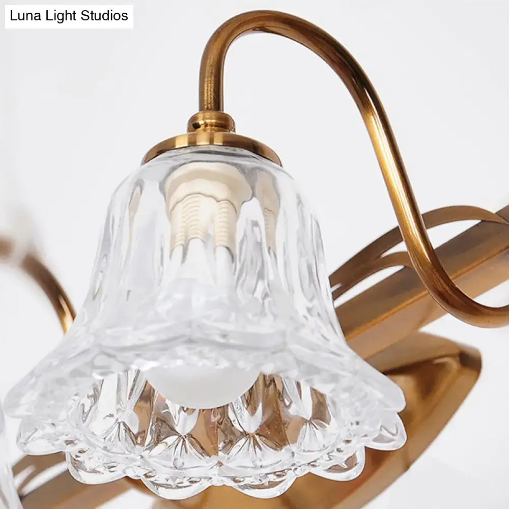 Vintage style wall light featuring a clear intricately cut glass bell-shaped lampshade with a gold brass frame and curved arm