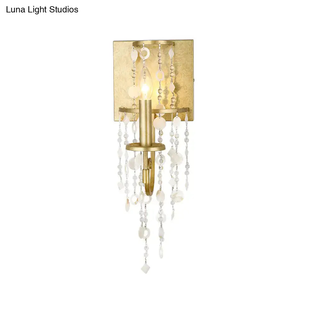 Vintage style gold wall sconce featuring a crystal beaded strand with cascading clear and frosted beads for bedroom lighting