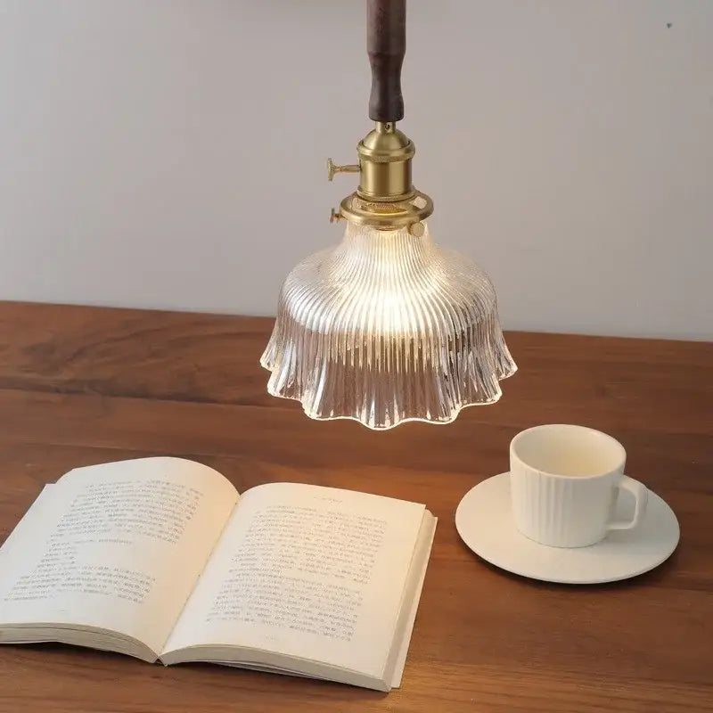 Vintage walnut and brass glass led pendant lamp with a clear ribbed glass shade hanging above an open book