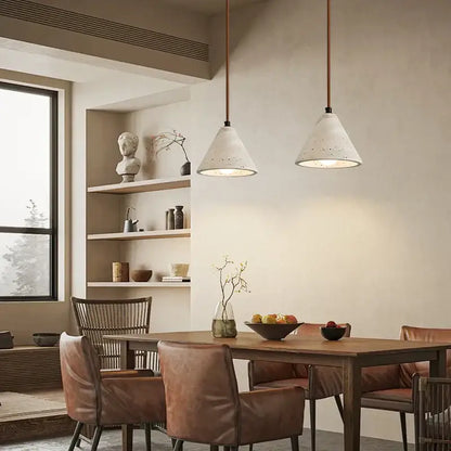Two vintage hanging led pendant lights with white speckled concrete shades and copper cords above dining table
