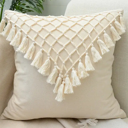 Cream-colored tufted cushion cover with diamond-patterned macrame top and tassels for wabi-sabi living room decor