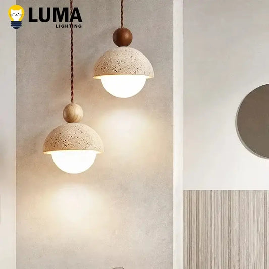 Two beige natural stone pendant lights with wooden accents hang from twisted cords providing sculptural presence
