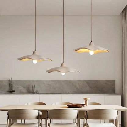 Three elegant off-white ceramic pendant lights with scalloped edges and natural wood material for dining room