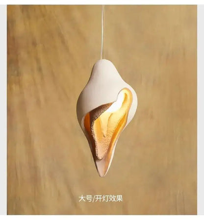 Wabi sabi cream gypsum conch pendant lamp featuring a sleek white ceramic shell design with warm golden glow interior