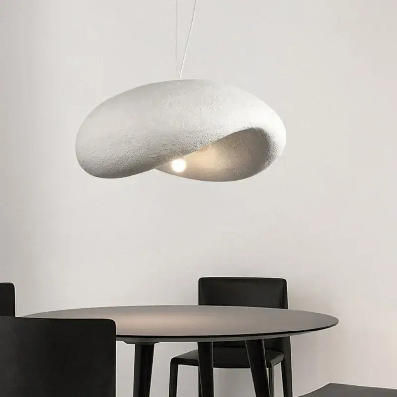 A cream style led pendant light with a cloud shape and textured surface hangs above the dining table decorbites cream style