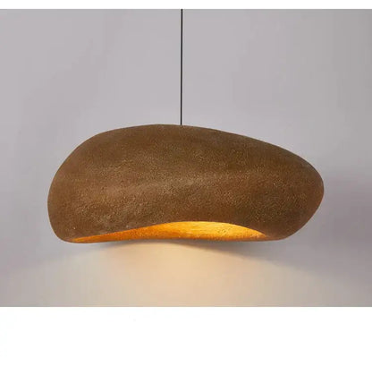 A warm amber-glowing decorbites handmade polystyrene indoor pendant light with textured earthy-brown ceramic body