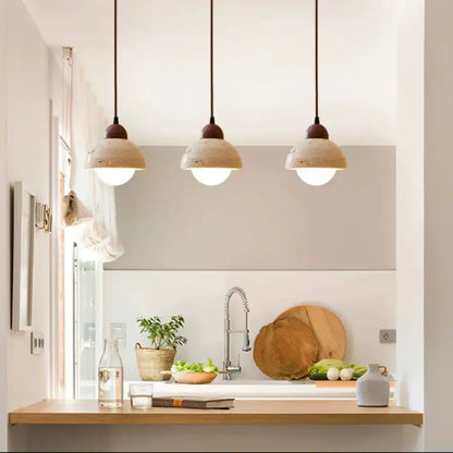 Three beige textured ceramic decorbites cave stone pendant lights with dark brown cords above a kitchen counter