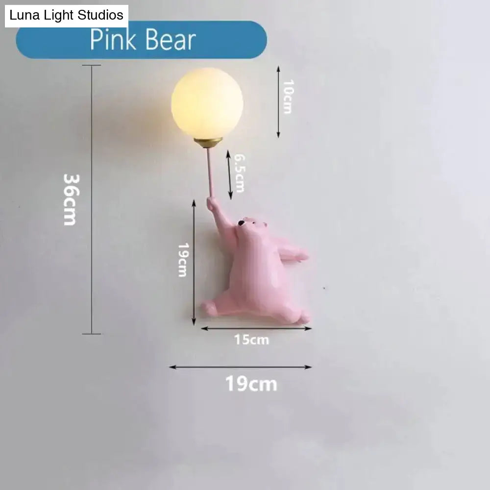 A whimsical pink polka dot girl wall lamp with matte bear holding frosted glass bulb on metallic stem for bedroom