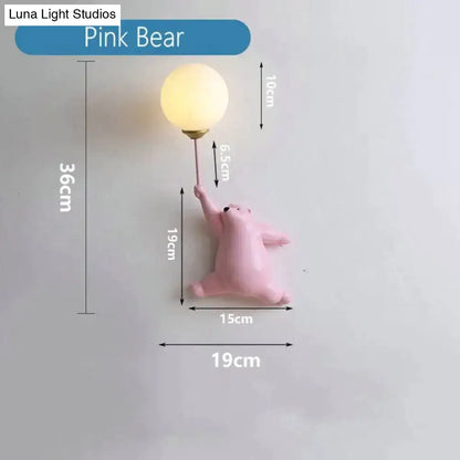 A whimsical pink polka dot girl wall lamp with matte bear holding frosted glass bulb on metallic stem for bedroom