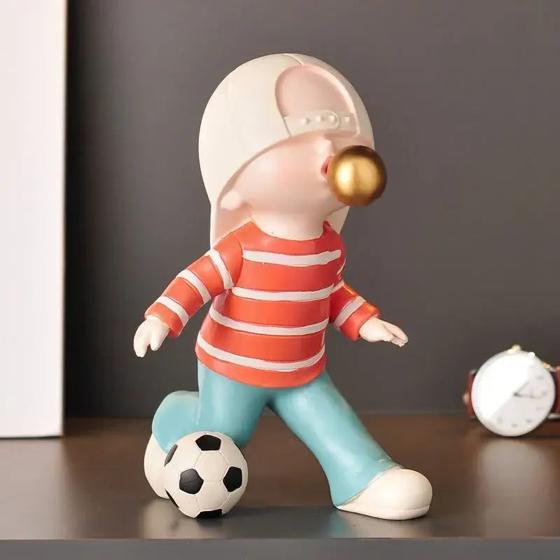 Whimsical resin boys sports statue of child in orange striped shirt blowing golden bubble gum ball for decorbites boys sports decor