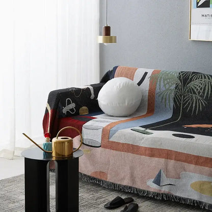 Whimsical space themed decorbites knit sofa blanket with abstract black white peach and blue pattern and fringed edges