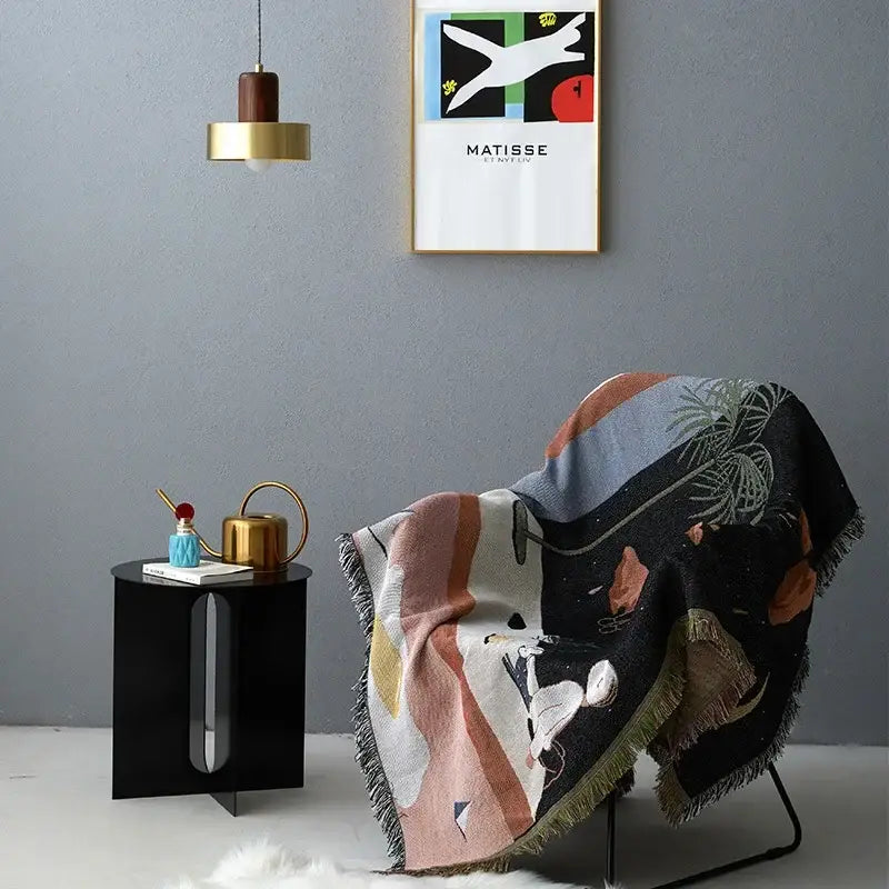A cozy decorbites knit sofa blanket in black with colorful geometric shapes draped over an armchair for living room decor