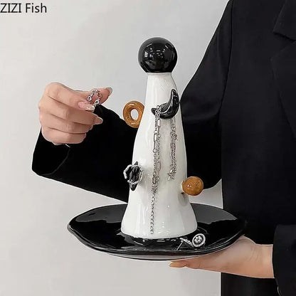 A sleek white and brown ceramic jewelry display stand with glossy black top and decorative orange accents for necklace display