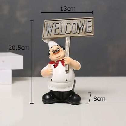 A cheerful white bearded chef resin figure with red bow tie holding a weathered wooden welcome sign for kitchen decor