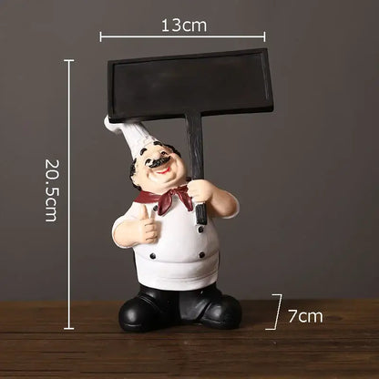 A cheerful white bearded chef resin figure in uniform holding a black chalkboard sign for kitchen decor