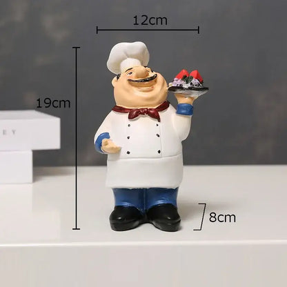 A cheerful bearded chef resin figure with white hat red bow tie and blue pants holding a dessert tray for kitchen decor