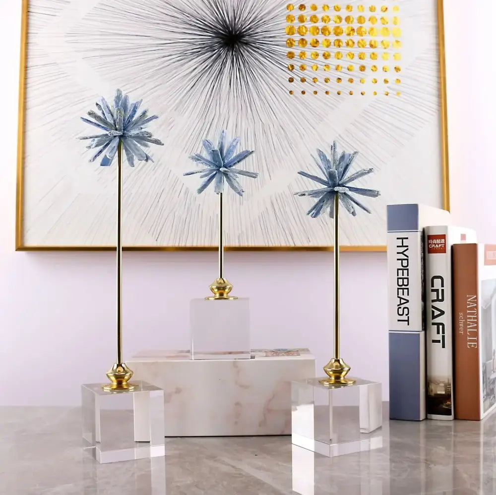 Three elegant blue crystal starburst home decor figurines on gold stands with clear acrylic bases for living room display