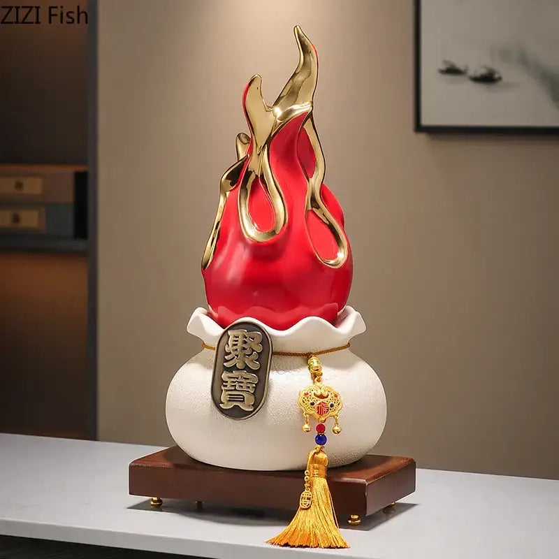 Red and gold flame-shaped feng shui ornament with white ceramic base and gold tassel for living room decor