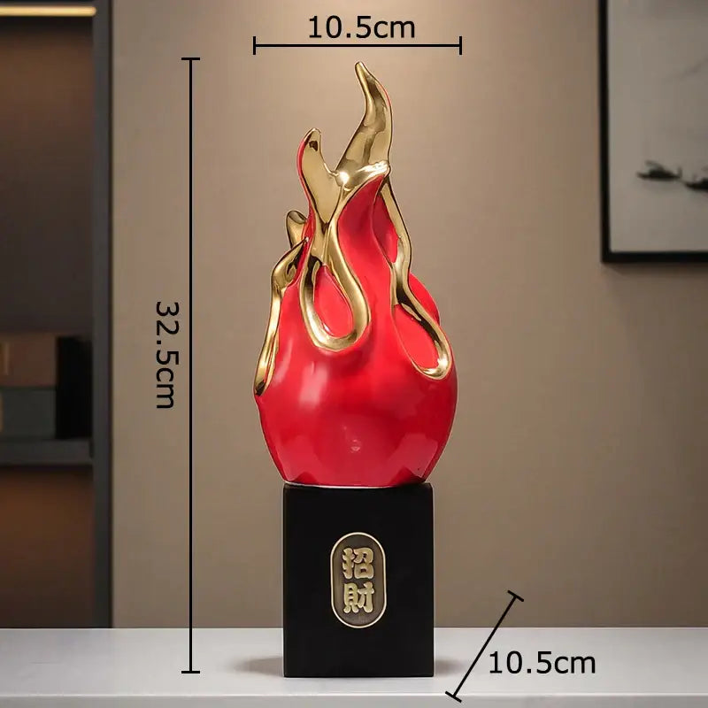 A glossy red and gold flame-shaped feng shui ornament with black base and chinese characters for living room decor