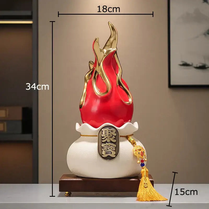 Red and gold flame-shaped feng shui ornament with white ceramic base and golden tassel for living room decor