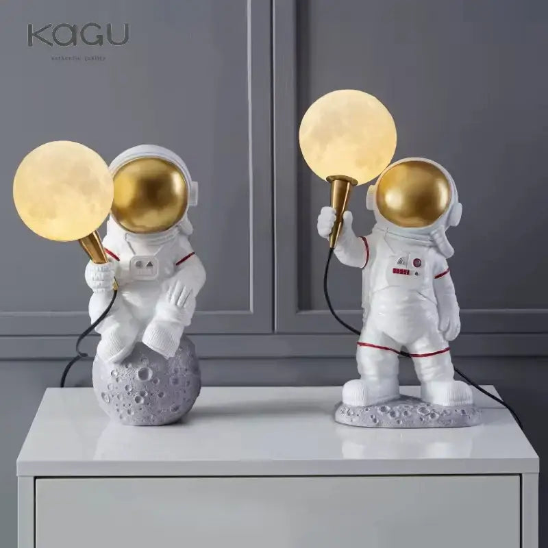 White and gold decorbites astronaut moon figurines holding glowing lamps on textured lunar base for bedroom light