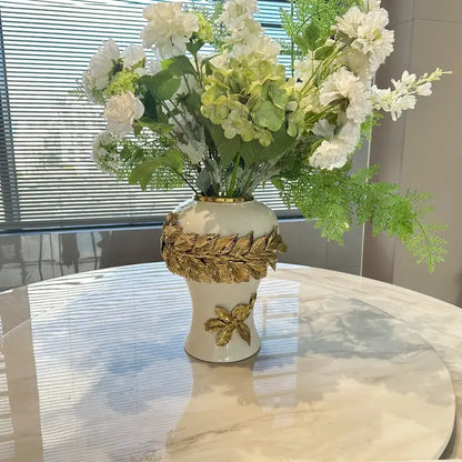 Cream-colored leaves ceramic flower vase with decorbites golden leaves and golden rim holding white flowers for living room decor