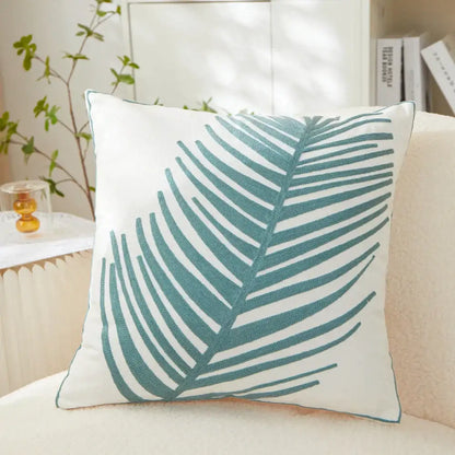 White cushion pillow cover with teal embroidered leaf design for living room decor featuring embroidered leaf pillow detail
