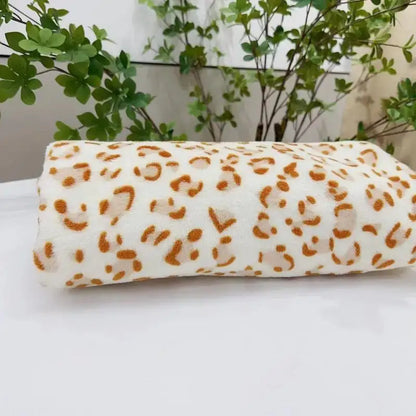 A soft rolled-up white fleece blanket with bold orange leopard print decorbites leopard print warm throw