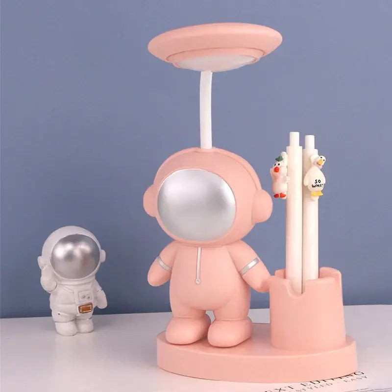Pink astronaut desk lamp with silver visor and white pen holder featuring pencil sharpener for bedroom study decorbites astronaut study