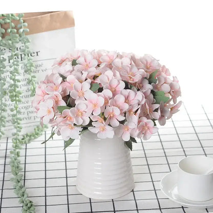 Delicate white begonia silk flower bouquet with pink and yellow artificial flowers in a white ceramic vase decor