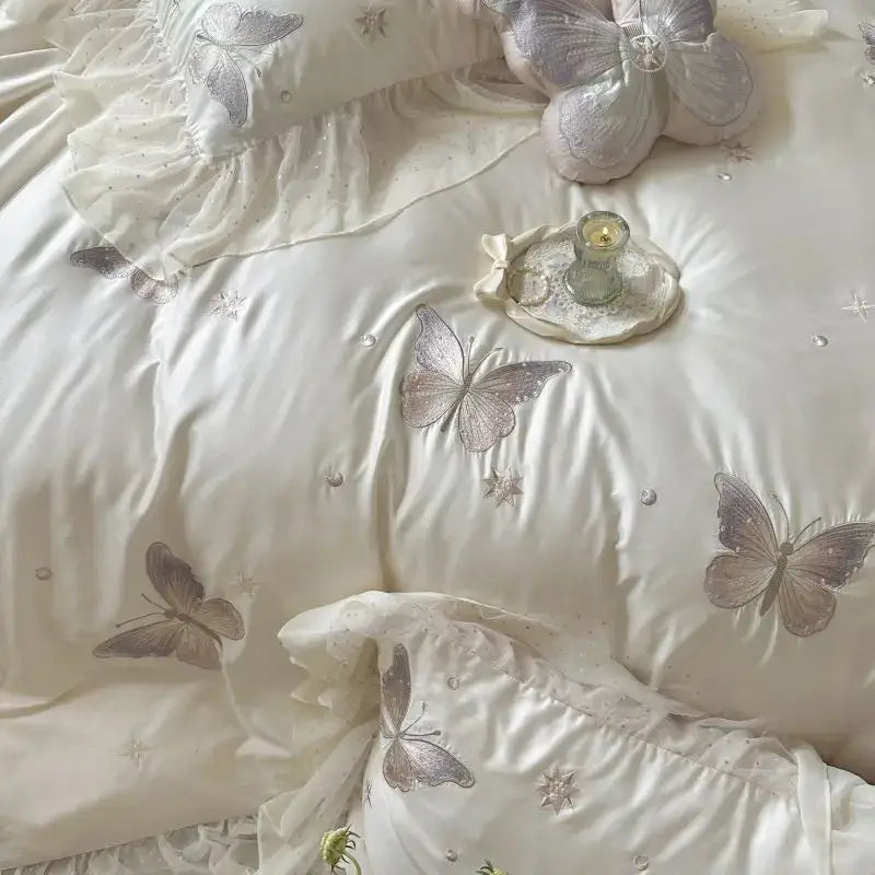 Cream-colored quilted bedding set with decorbites butterfly lace ruffles and delicate gray embroidery accents
