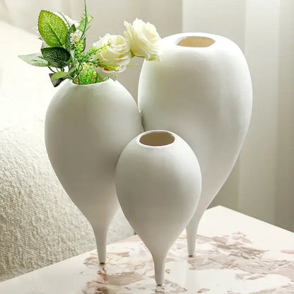 Three elegant white ceramic balloon geometric vases with slender legs in a geometric vase trio for living room decor