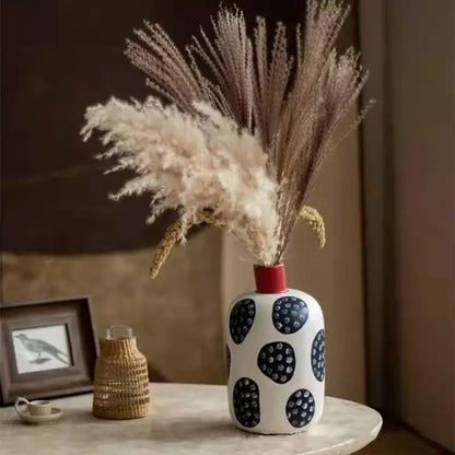 White ceramic polka dot vase with colorful graffiti lines and red rim holding dried pampas grass for living room decor