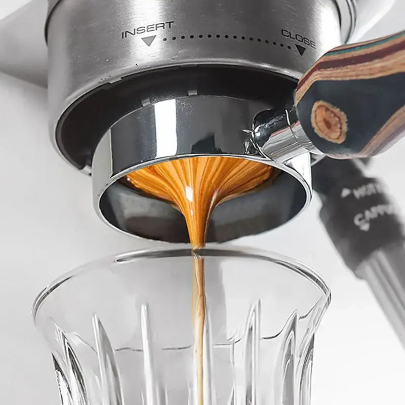 A sleek stainless steel espresso machine with wooden handle pours rich coffee using white circular decorbites coffee filter papers