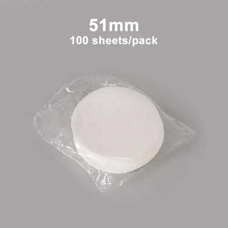 A stack of 51mm white circular disposable decorbites coffee filter papers in clear plastic packaging