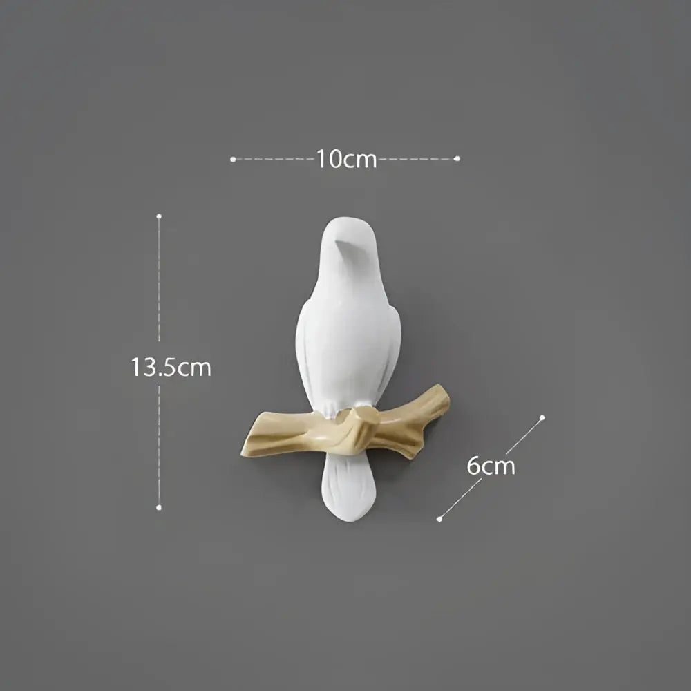 White decorbites bird resin hanger showing a white ceramic bird figurine perched on a golden brown branch