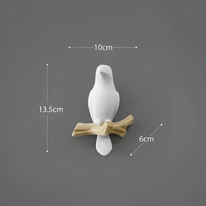 White decorbites bird resin hanger showing a white ceramic bird figurine perched on a golden brown branch